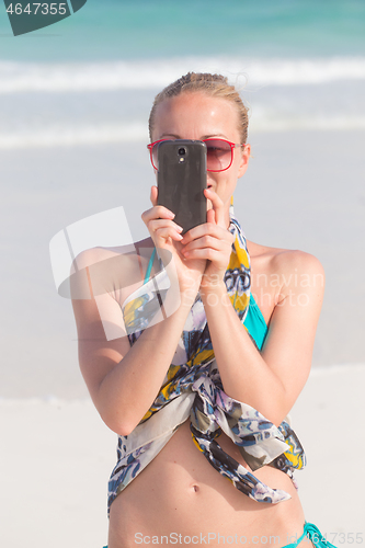 Image of Beautiful caucasian woman taking a photo on tropical beach summer vacations using her cell phone.