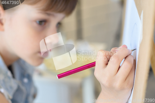 Image of close-up of the hand of a girl drawing a pencil on an easel