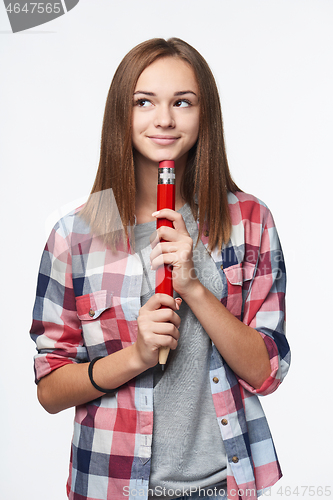 Image of Smiling girl holding big pencil and looking to the side