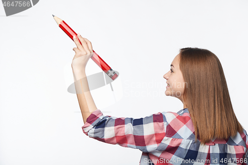 Image of Profile of a teen girl writing with big pencil on blank copy space