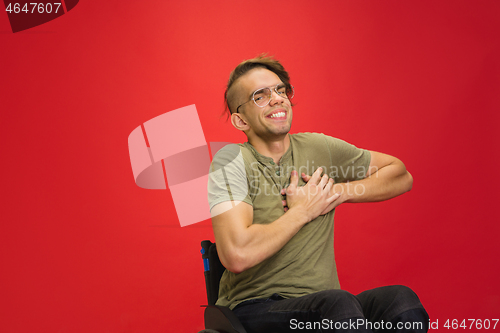 Image of Caucasian young man\'s portrait isolated on red studio background. Human emotions concept