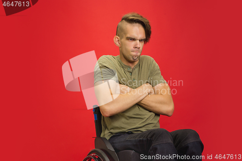 Image of Caucasian young man\'s portrait isolated on red studio background. Human emotions concept