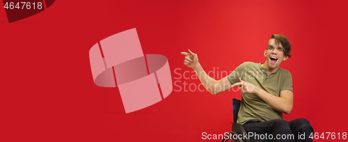 Image of Caucasian young man\'s portrait isolated on red studio background. Human emotions concept