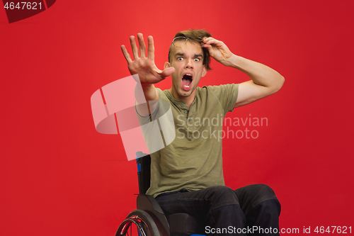 Image of Caucasian young man\'s portrait isolated on red studio background. Human emotions concept