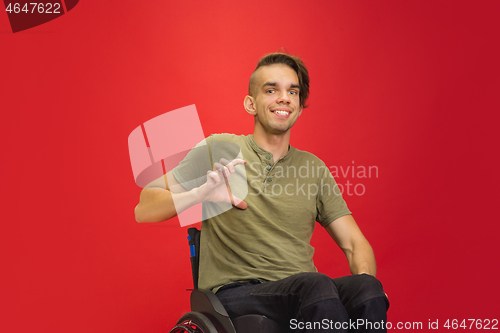 Image of Caucasian young man\'s portrait isolated on red studio background. Human emotions concept