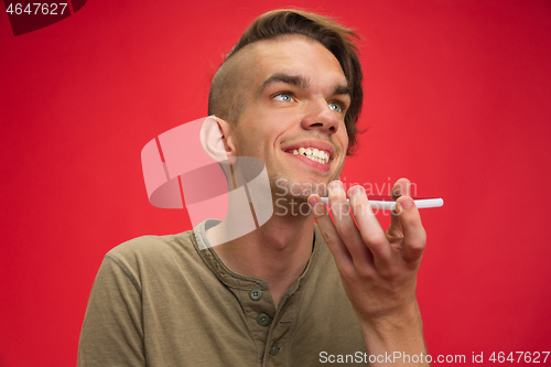 Image of Caucasian young man\'s portrait isolated on red studio background. Human emotions concept