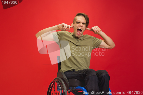 Image of Caucasian young man\'s portrait isolated on red studio background. Human emotions concept