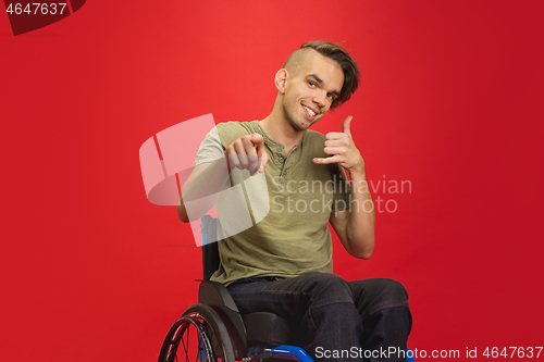 Image of Caucasian young man\'s portrait isolated on red studio background. Human emotions concept