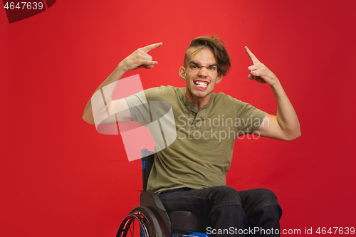 Image of Caucasian young man\'s portrait isolated on red studio background. Human emotions concept