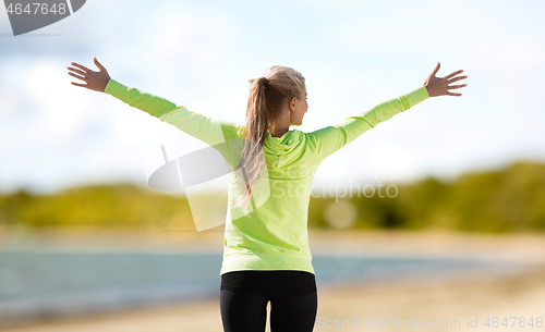 Image of happy woman in sports clothes on beach