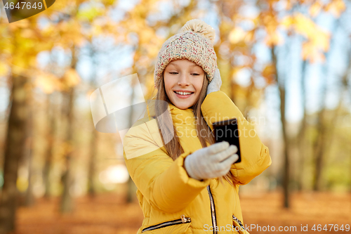 Image of girl taking selfie by smartphone at autumn park