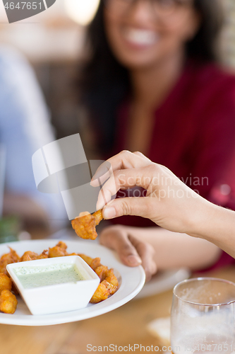 Image of hand with snack and dip sauce at restaurant