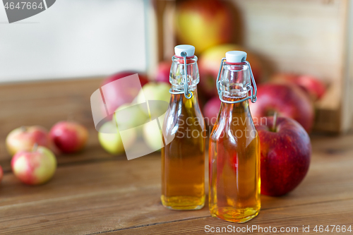 Image of bottles of apple juice or vinegar on wooden table