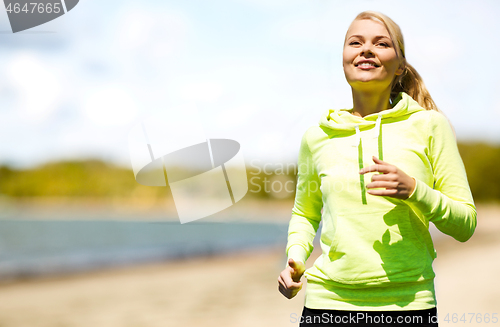 Image of smiling woman running along beach