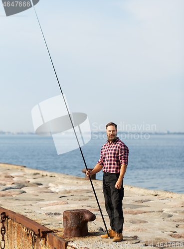 Image of bearded fisherman with fishing rod on sea pier