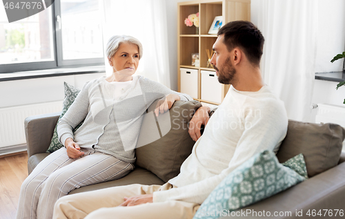 Image of senior mother talking to adult son at home