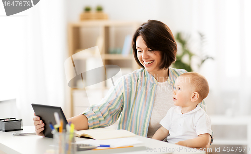 Image of working mother with tablet pc and baby at home