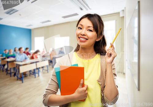 Image of asian female teacher with books at school