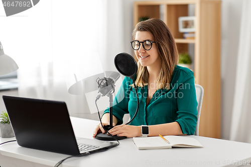 Image of woman with microphone recording podcast at studio