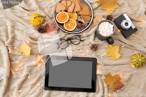 Image of tablet computer, hot chocolate and autumn leaves