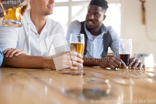 Image of male friends drinking beer at bar or pub