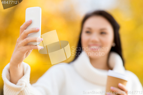 Image of woman taking selfie by smartphone in autumn park