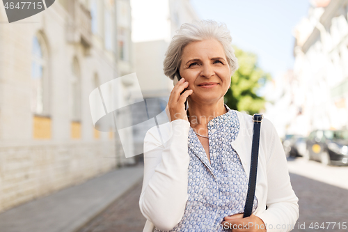 Image of senior woman calling on smartphone in city