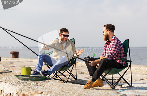 Image of happy male friends with rods talking about fishing