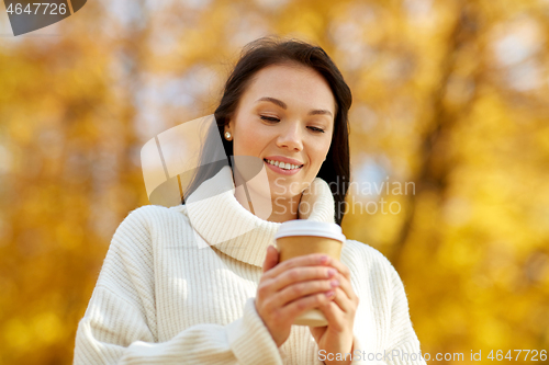 Image of woman drinking takeaway coffee in autumn park