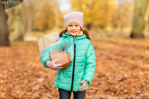 Image of happy little girl with pumpkin at autumn park