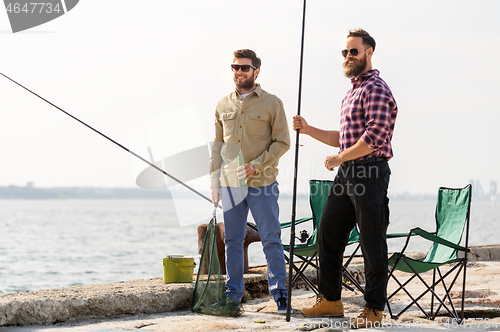 Image of male friends with fishing rods and beer on pier