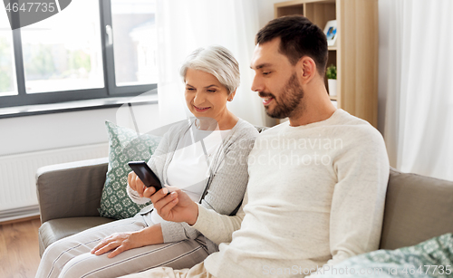 Image of old mother and adult son with smartphone at home