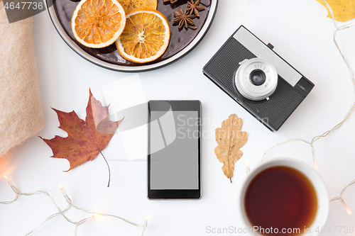 Image of smartphone, tea, camera, cookies and autumn leaves