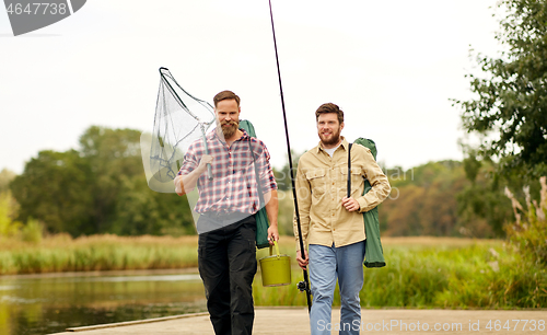 Image of friends with fishing rods and net at lake or river