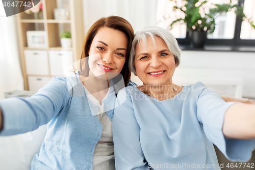 Image of senior mother and adult daughter taking selfie