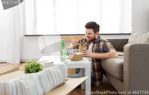 Image of smiling man eating takeaway food at new home