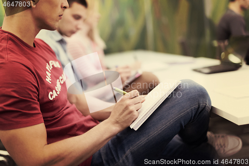 Image of male student taking notes in classroom