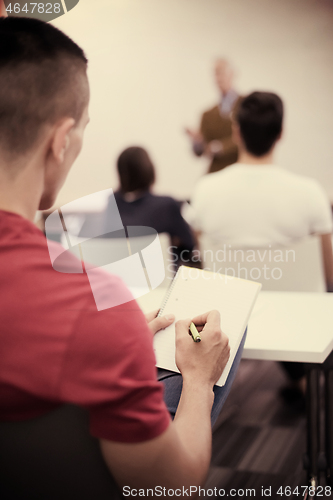 Image of male student taking notes in classroom