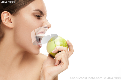 Image of portrait of attractive caucasian smiling woman isolated on white studio shot eating green apple