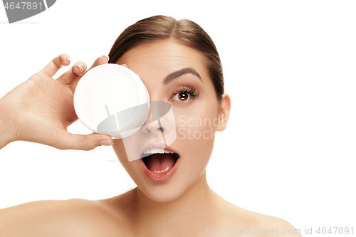 Image of Cute girl preparing to start her day. She is applying moisturizer cream on face.