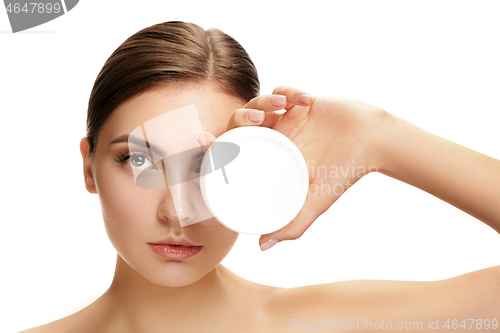 Image of Cute girl preparing to start her day. She is applying moisturizer cream on face.