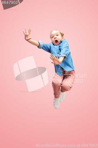 Image of Young scared caucasian teen girl jumping in the air, isolated on pink studio background.