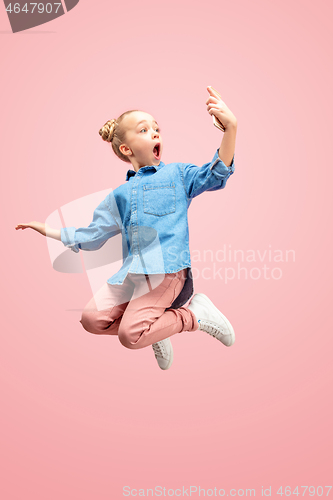 Image of Young happy caucasian teen girl jumping with phone in the air, isolated on pink studio background.