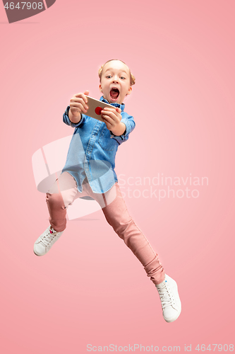 Image of Young happy caucasian teen girl jumping with phone in the air, isolated on pink studio background.