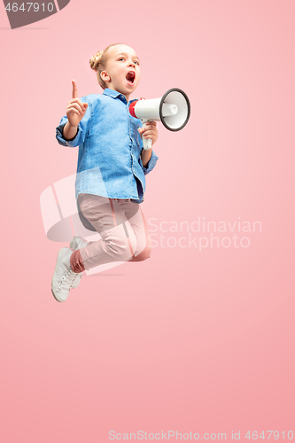 Image of Beautiful young child teen girl jumping with megaphone isolated over pink background