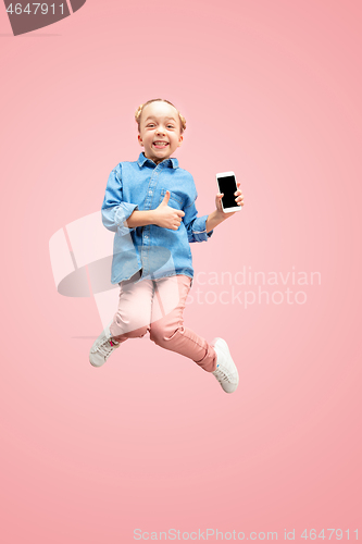 Image of Young happy caucasian teen girl jumping with phone in the air, isolated on pink studio background.