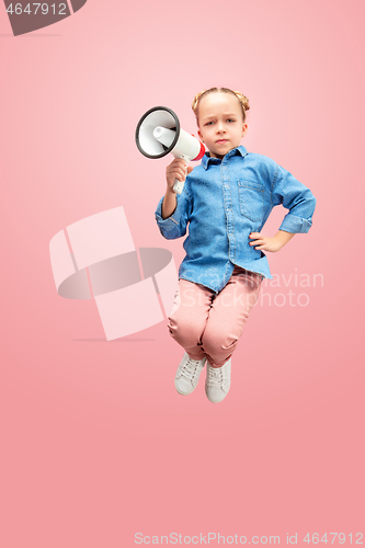 Image of Beautiful young child teen girl jumping with megaphone isolated over pink background