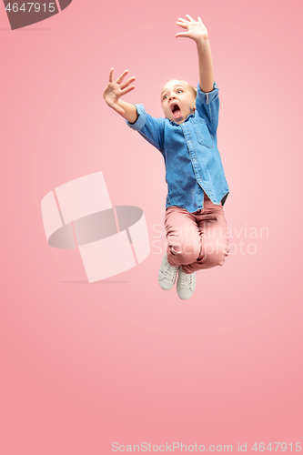 Image of Young scared caucasian teen girl jumping in the air, isolated on pink studio background.