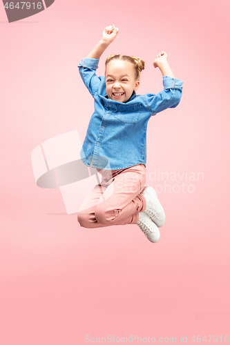 Image of Young happy caucasian teen girl jumping in the air, isolated on pink studio background.