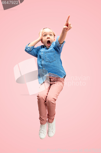 Image of Young happy caucasian teen girl jumping in the air, isolated on pink studio background.